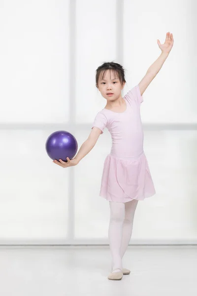 Азійська дівчинка в рожевій сукні тримає м'яч. — стокове фото