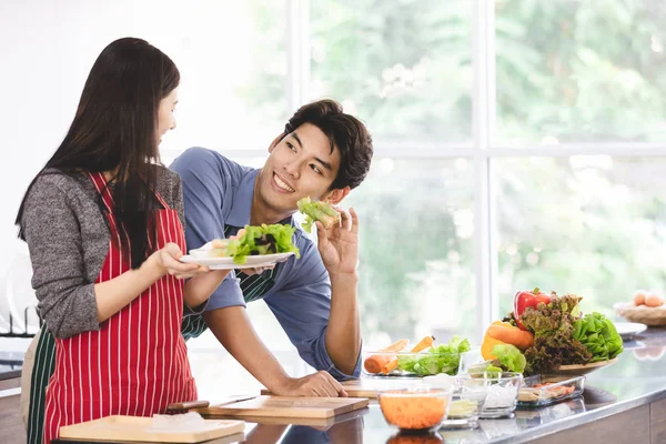 Casal em avental fazer rolos de salada juntos — Fotografia de Stock