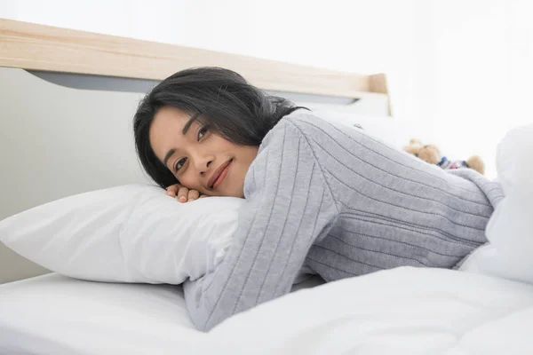 Aziatische vrouw ligt op een kant op bed in slaapkamer — Stockfoto