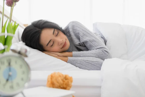 Mulher asiática encontra-se de lado na cama no quarto — Fotografia de Stock