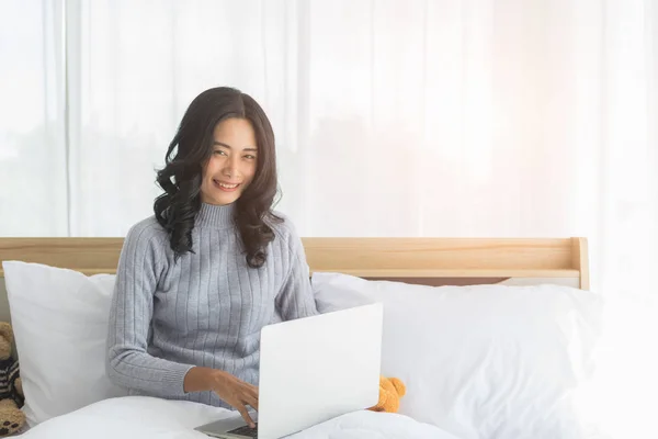 Mujer asiática sentada y usando portátil en el dormitorio . — Foto de Stock