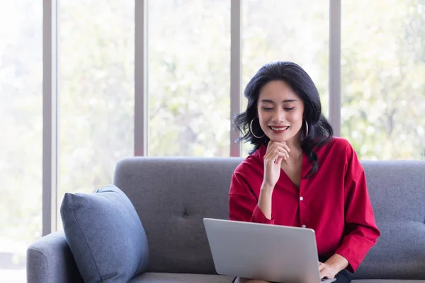 Mulher asiática usando notebook computador no sofá — Fotografia de Stock