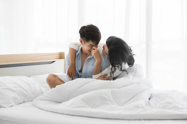 Couple sits on bed, they hug each other by love