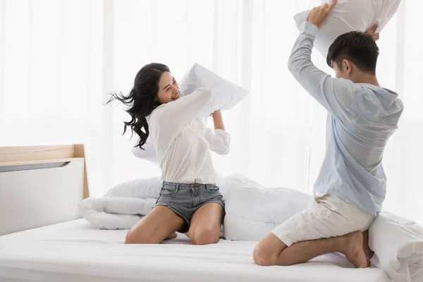 Asian couple sits on bed, They have pillow fight — Stock Photo, Image