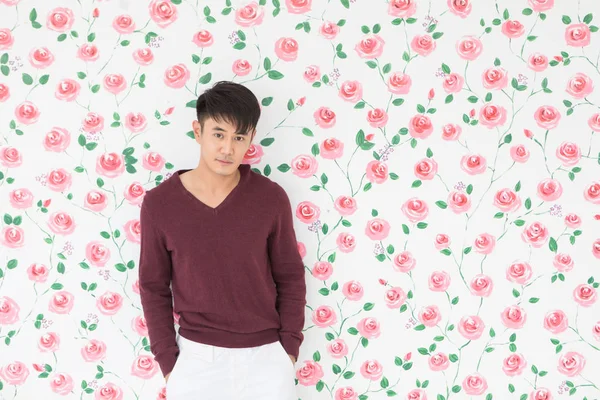 Aziatisch man staan, poseren op bloemen achtergrond — Stockfoto
