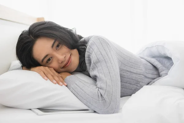 Aziatische vrouw ligt op een kant op bed in slaapkamer — Stockfoto