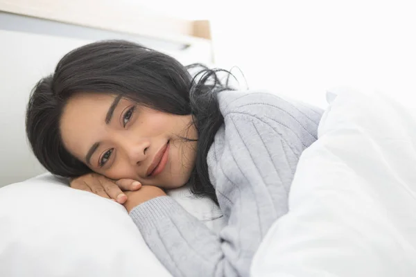 Aziatische vrouw ligt op een kant op bed in slaapkamer — Stockfoto