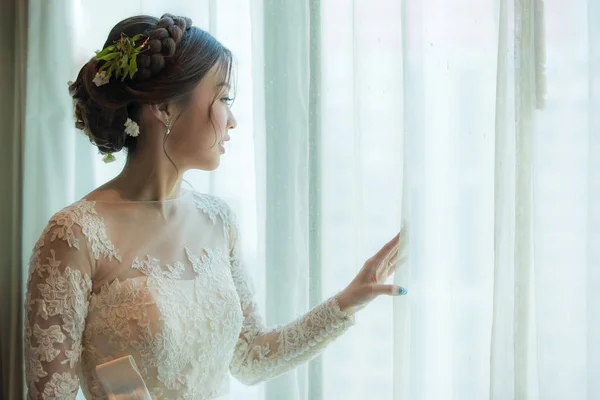 Noiva asiática de pé perto da janela no camarim — Fotografia de Stock
