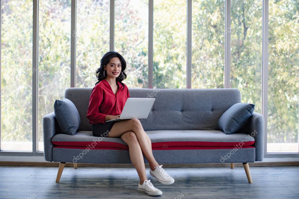 Asian woman using notebook computer on sofa