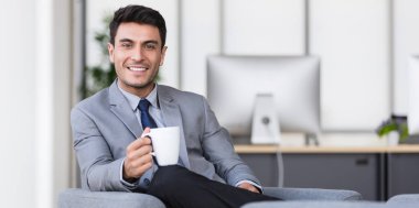 İşadamı ofiste kahve içiyor.