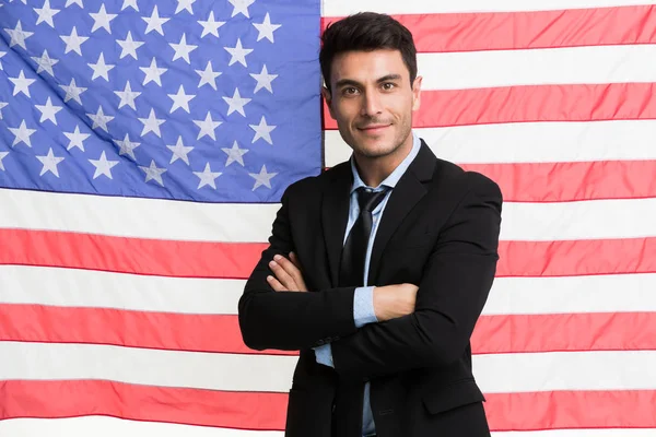 Businessman cross arms in front of American flag