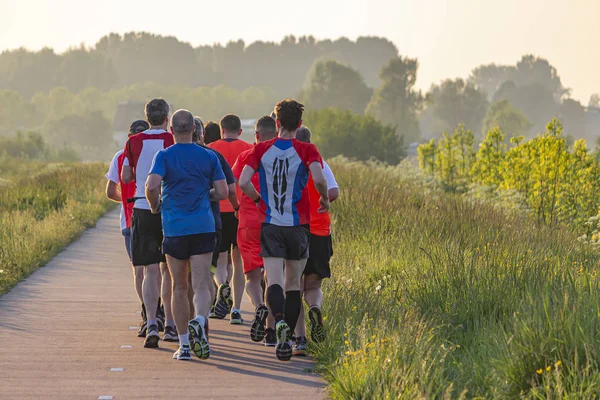 A group of runners enjoy the evening sun on the footpath along lake Noordhovense Plas in Zoetermeer, Netherlands
