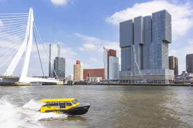 Arka planda Erasmus köprüsü ve Hotel nhow Rotterdam ile sarı bir yüksek hızlı su taksi