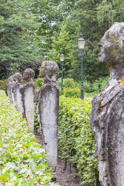 Several old and weathered stone statues of persons on a row (portrait photographed) in a park or Bouvigne Castle at Breda, Netherlands