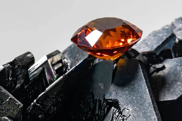 Padparadsha renkli Corundum değerli taşının fotoğrafı, bir Spinner şeklinde kesilmiş, siyah silikon karpit yüzeyine yerleştirilmiş.