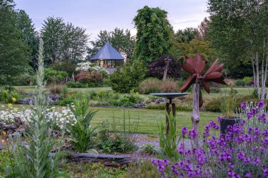 Groningen 'deki Harkstede köyünün yakınlarındaki ağaçların ve çiçek açan çalıların bulunduğu bu güzel bahçedeki alacakaranlık boyunca renkli çiçek tarlaları.