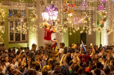 Moskova, Rusya - 1 Temmuz 2018: FIFA Dünya Kupası Rusya. Kadın sokak lambası tırmanıyor. Farklı ülkelerin futbol taraftarları Moskova'da İspanya Nicholas Street üzerinde Rus ekibi zaferi kutlamak