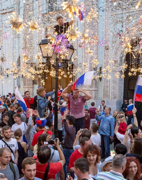 Moskova, Rusya - 1 Temmuz 2018: Rusya'da FIFA Dünya Kupası. Sokak lambası bayrağı olan adam. Farklı ülkelerin futbol taraftarları İspanya Nicholas Street Rus takımının zaferi kutlamak