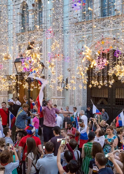 Moskova, Rusya - 1 Temmuz 2018: Rusya'da FIFA Dünya Kupası. Sokak lambası bayrağı olan adam. Farklı ülkelerin futbol taraftarları İspanya Nicholas Street Rus takımının zaferi kutlamak