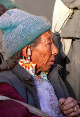 Lamayuru, Hindistan - 17 Haziran 2012: Lamayuru Manastırı 'ndaki Budist Yuru Kabgyat festivalini izleyen gözlemciler arasında geleneksel giysiler ve mücevherlerle dua eden yaşlı ladakhi kadınları