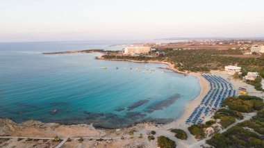 Landa plajı, Ayia Napa, Famagusta, Kıbrıs 'ın havadan kuş bakışı görüntüsü. Gündoğumunda turistlerin uğrak yeri altın kumsaldır. Güneş yatakları, Makronissos ve Agia Napa arasında deniz restoranları vardır. Yaz tatillerinde yukarıdan..