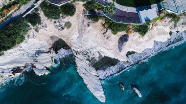 Simgesel Yapı büyük beyaz tebeşir rock Valilik Beach, Limasol, Kıbrıs hava görünümünü. Dik taş kayalıklarla ve derin mavi deniz dalgaları koyları ve Kalimnos balık restaurant yukarıdan yanındaki karanlık kum kırma.