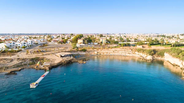 Aerial bird\'s eye view of Kapparis (fireman\'s) beach in Protaras, Paralimni, Famagusta, Cyprus. The famous tourist attraction golden sandy Kaparis bay with boats, sunbeds, restaurants, water sports, people swimming in sea on summer holidays, from abo