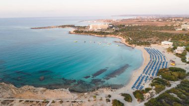 Landa plajı, Ayia Napa, Famagusta, Kıbrıs 'ın havadan kuş bakışı görüntüsü. Gündoğumunda turistlerin uğrak yeri altın kumsaldır. Güneş yatakları, Makronissos ve Agia Napa arasında deniz restoranları vardır. Yaz tatillerinde yukarıdan..