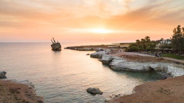 Günbatımında Kıbrıs Rum Kesimi 'nin Pegeia kentindeki terk edilmiş gemi enkazı EDRO III' e kuşların bakış açısı. Pafos 'taki Coral Bay yakınlarındaki deniz mağaralarında Peyia kayalıklarında karaya oturmuş paslı gemi enkazı..