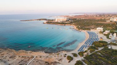 Landa plajı, Ayia Napa, Famagusta, Kıbrıs 'ın havadan kuş bakışı görüntüsü. Gündoğumunda turistlerin uğrak yeri altın kumsaldır. Güneş yatakları, Makronissos ve Agia Napa arasında deniz restoranları vardır. Yaz tatillerinde yukarıdan..