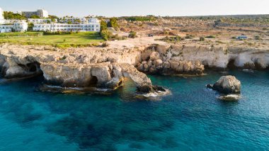 Yukarıdan Kıbrıs Rum Kesimi 'nin Cavo Greco, Ayia Napa, Famagusta kentindeki kıyı şeridi ve tarihi Aşk Köprüsü, uluslararası heykel parkı ve deniz mağaralarının havadan görünüşü. Kuş bakışı turistik yer kayalık kayalık doğal oluşum Ammochostos kayalık kemer
