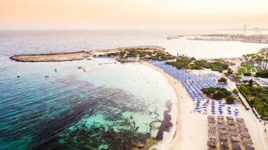 Ünlü Makronissos sahil şeridi Ayia Napa, Famagusta, Kıbrıs 'ın havadan kuş bakışı manzarası. Günbatımında Agia Napa 'da altın kum, güneşlik, deniz restoranları ve yaz tatilleri ile turistik mekan Makronisos Körfezi..