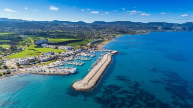 Latchi limanı, Akamas yarımadası, Polis Chrysochous, Paphos, Kıbrıs 'ın havadan kuş bakışı görüntüsü. Tekneleri ve yatları olan Latsi limanı, balık restoranları, gezinti güvertesi, plaj turistik alanı ve yukarıdan gelen dağlar..