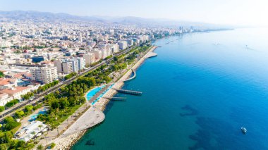 Kıbrıs Rum Kesimi 'nin Limasol şehir merkezindeki Molos Promenade parkının hava görüntüsü. İskelenin kuş bakışı manzarası, sahil yolu, palmiye ağaçları, Akdeniz, rıhtım, kentsel ufuk çizgisi ve yukarıdan liman.