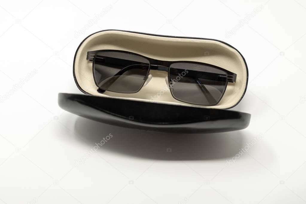 An open glasses case, containing a pair of sunglasses on a white background
