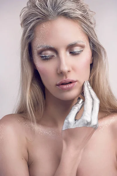 winter beauty portrait of woman with silver snowy hair and make up touching her face with hand