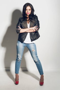 Studio poz tam uzunlukta güzel esmer model giyen portre siyah deri ceket, kot pantolon ve kırmızı topuklu