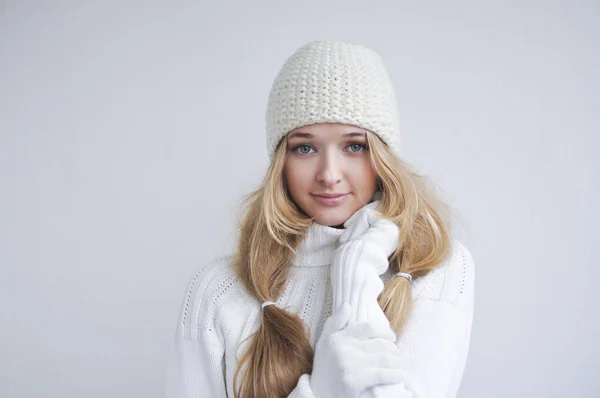 smiling blonde woman in winter gloves, knitted hat and sweater holding her hands on chin