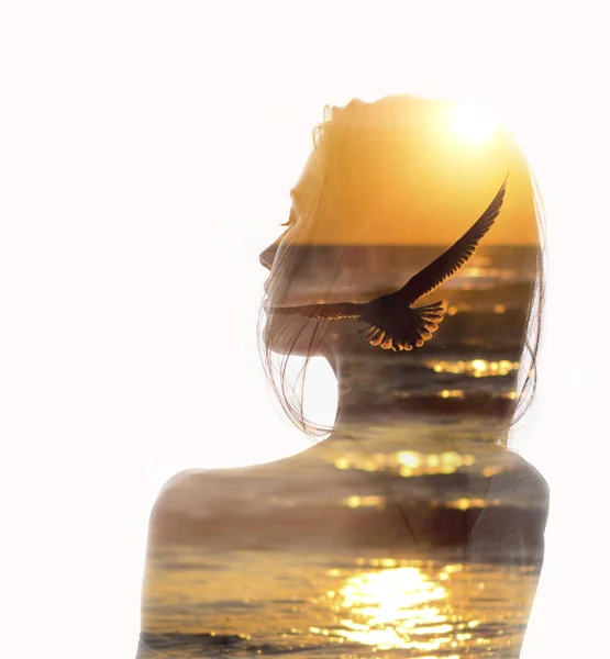Double exposure portrait of woman and flying bird in sunset reflecting in ocean. Concept of human with nature unity. Ecology, freedom, environment