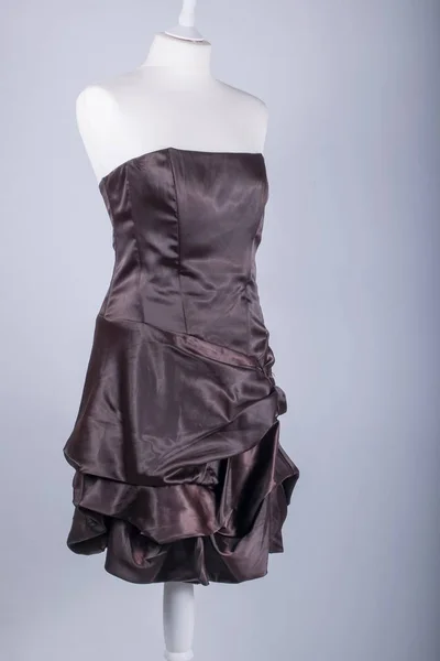 A Tailors Mannequin dressed in a Brown Satin Dress