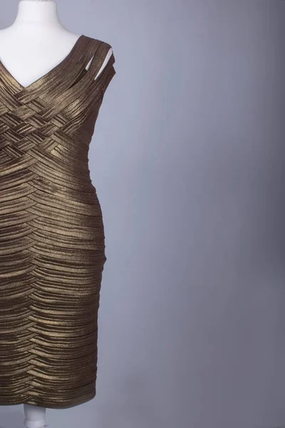 A Tailors Mannequin dressed in a Gold Shiny Dress