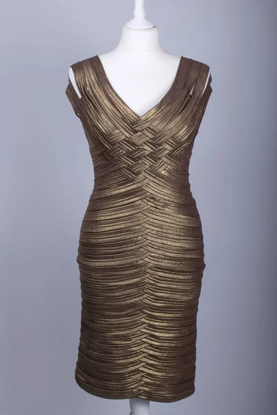 A Tailors Mannequin dressed in a Gold Shiny Dress