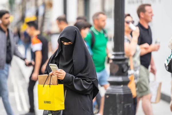 Londra, Ingiltere, Temmuz, 2019. Londra 'da bir Müslüman kadın bir niqab giyen, cep telefonu kullanarak alışveriş yaparken. Oxford Caddesi