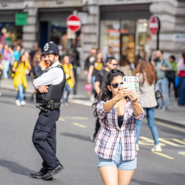 Londres, Reino Unido, 14 de julho de 2019. Uma rapariga em Londres tira uma selfie à frente da polícia. Foco suave . — Fotografia de Stock