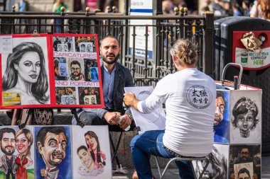 Londra, Ingiltere, 14 Temmuz 2019. Sokak sanatçısı modelleri portre çizmeye. Farklı stiller ile karikatürist çizim insanlar