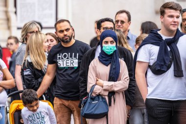 Londra, İngiltere, 28 Temmuz 2019. Sokak gösterilerini izleyen insanlar. Kirlilik yüz maskesi takan genç Asyalı kadın