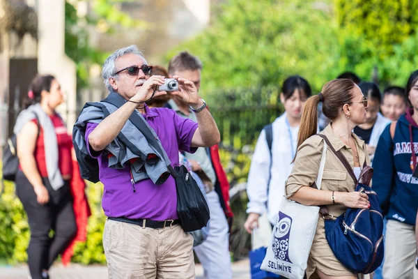 Cambridge, İngiltere, 1 Ağustos 2019. Kings Koleji önünde güneşli bir günde Cambridge caddesinde yürüyen ve fotoğraf çeken turistler