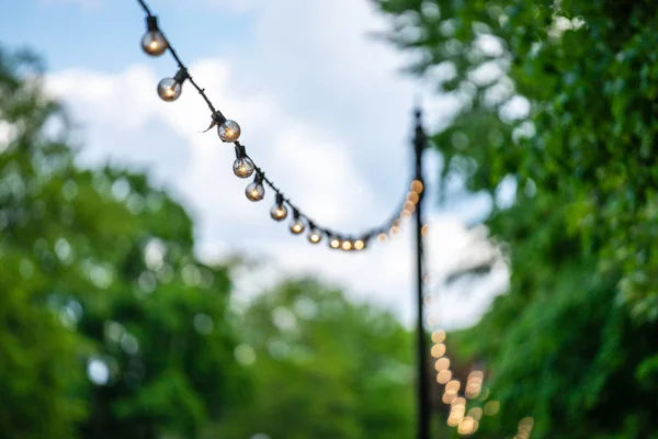 Background with blur street lights and garlands in park — Stock Photo, Image