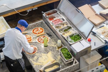 Pizzacı yukarıdan nefis kokulu bir pizza hazırlıyor.