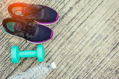 Şişe ve yeşil renk dumbbell yere ile spor ayakkabı 